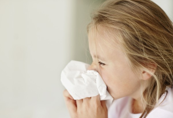 Girl (10-11) blowing nose. Photo : Momentimages