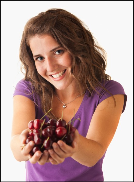 Young woman holding cherries. Photo : Mike Kemp