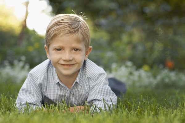 Portrait of boy (6-7) lying on grass. Photo : FBP