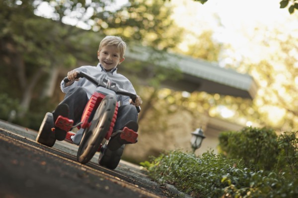 Portrait of boy (6-7) riding tricycle. Photo : FBP