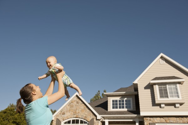 Mother lifting baby boy (6-11 months) outside home. Photo : FBP