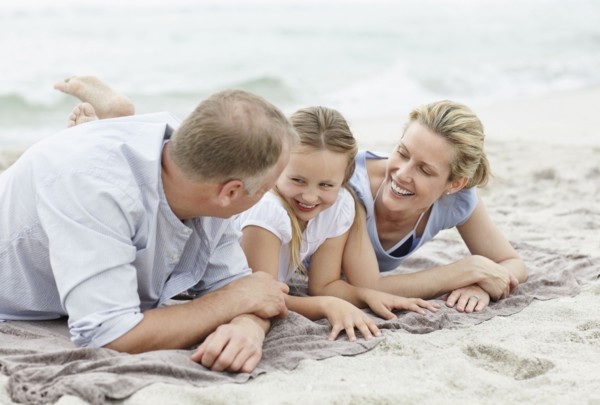 Girl (10-11) playing on beach with parents. Photo : Momentimages