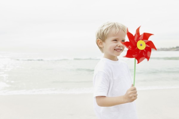 Boy (4-5) holding red pinwheel. Photo : Momentimages