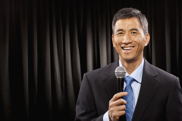 USA, Utah, Provo, Portrait of businessman with microphone standing in front of black curtain. Photo