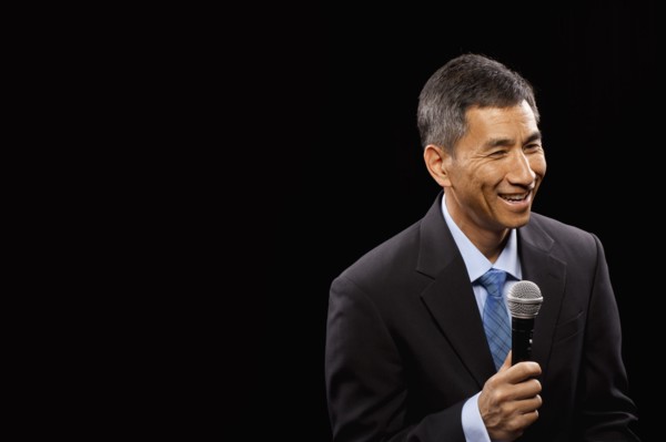 USA, Utah, Provo, Smiling businessman with microphone standing ion stage. Photo : FBP