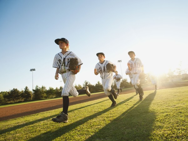 Baseball players (10-11) running on baseball diamond.