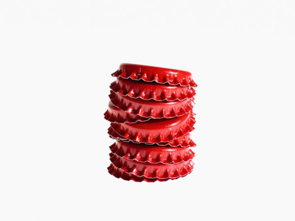 Studio shot of heap of red bottle caps. Photo : David Arky