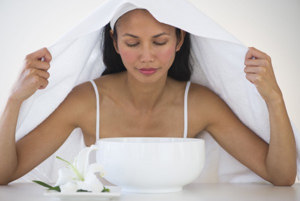 Woman under towel having steam beauty treatment.