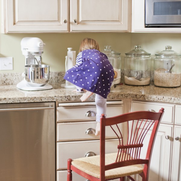 USA, Utah, Girl (2-3) climbing on cupboard in kitchen. Photo : Tim Pannell