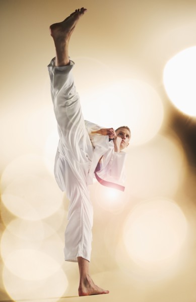 Young man performing karate kick.