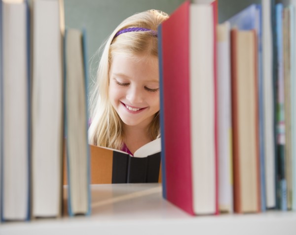 USA, New Jersey, Jersey City, View across the shelf showing girl (8-9) reading book. Photo : Jamie