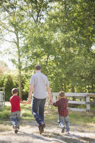 USA, New York, Flanders, Father with two sons (4-5, 8-9) walking in farm. Photo : Jamie Grill