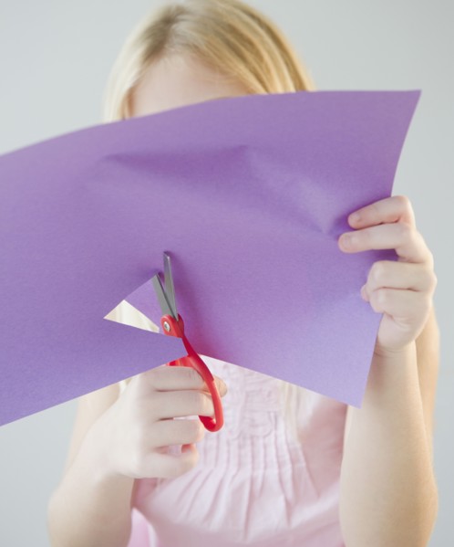 USA, New Jersey, Jersey City, Girl (8-9) cutting star shape in paper. Photo : Jamie Grill