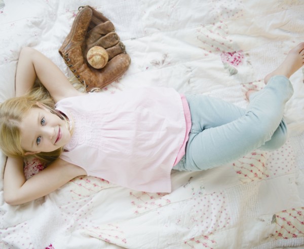 USA, New Jersey, Jersey City, Girl (8-9) laying beside baseball glove and ball. Photo : Jamie Grill