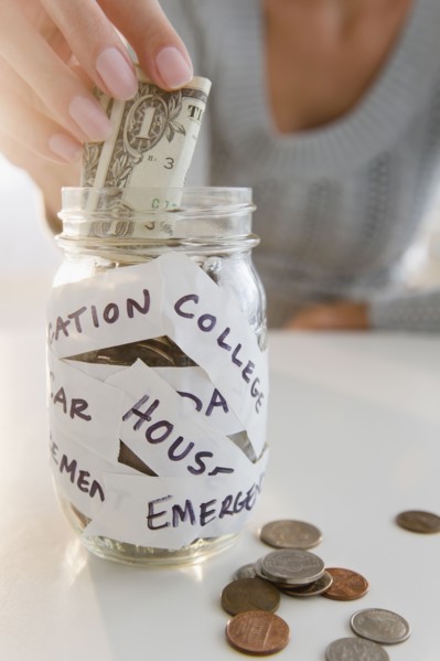 USA, New Jersey, Jersey City, Close-up view of woman's hand putting one dollar bill into piggybank.