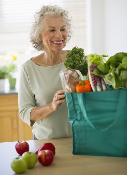 USA, New Jersey, Jersey City, Senior woman with grocery bag in kitchen.