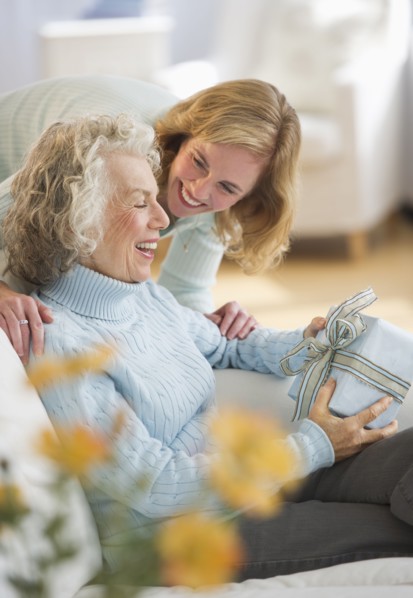 USA, New Jersey, Jersey City, Senior woman receiving present from daughter on sofa.