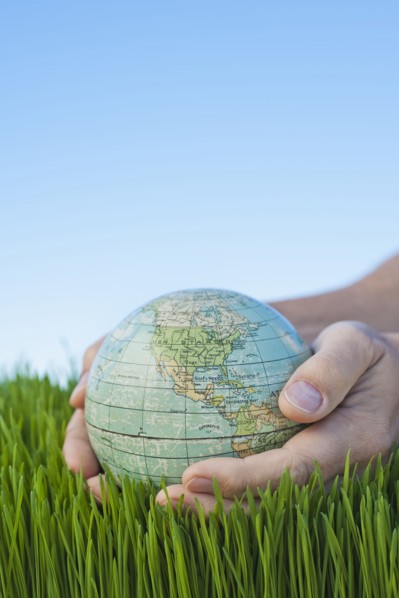 Male hands holding globe over grass.