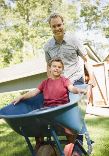 USA, New York, Flanders, father pushing wheel barrow with son (8-9) inside. Photo : Jamie Grill