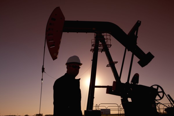 Silhouette of oil worker by pump jack on rig. Photo : Dan Bannister