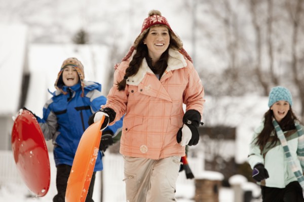USA, Utah, Provo, Teenage (16-17) girl running with sledge, boys and girls (10-11, 12-13) in