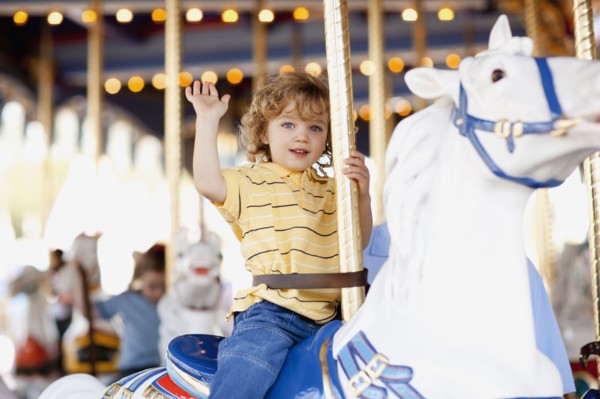 USA, California, Los Angeles, Boy (4-5) sitting on carousel's horse and waving. Photo : FBP