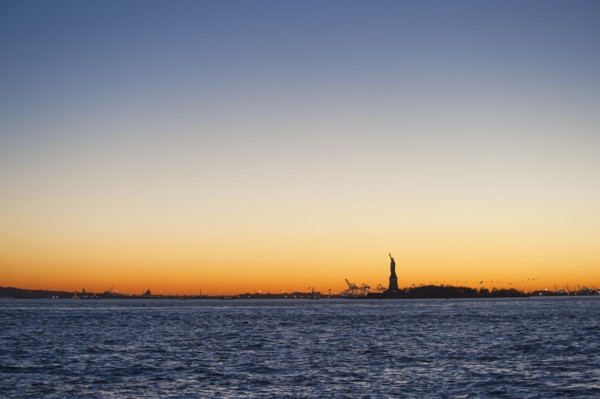 USA, New York City, Staten Island, Harbor and silhouette of Statue of Liberty in background.