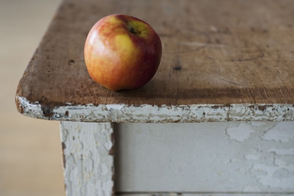 Apple on the egde of table.