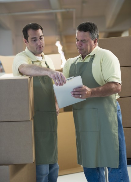 USA, New Jersey, Jersey City, Two male warehouse workers by stacked boxes.
