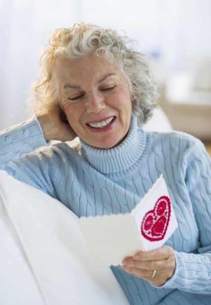 USA, New Jersey, Jersey City, Senior woman reading Valentines card in living room.