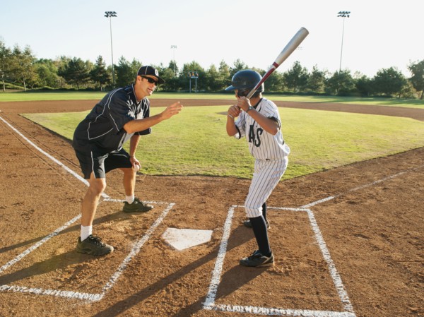 Baseball coach and boy (10-11) standing on baseball diamond.