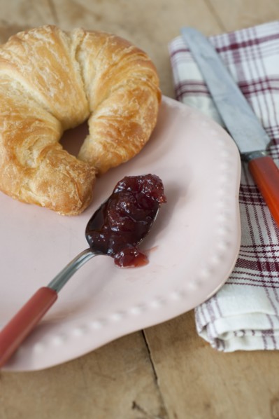 Croissant with jam on plate.