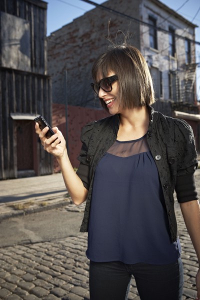 USA, New York City, Brooklyn, woman in street using phone. Photo : Shawn O'Connor