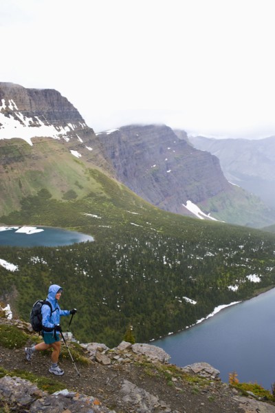 USA, Montana, Glacier National Park, Mid adult woman hiking with backpack during rain. Photo : Noah