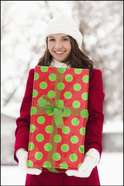 USA, Utah, Lehi, Portrait of young woman holding Christmas gift outdoors. Photo : Mike Kemp