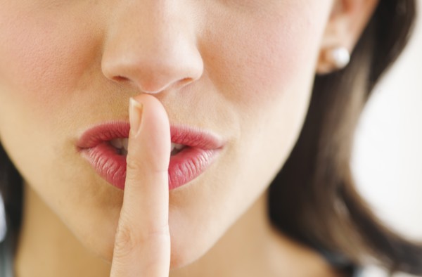 Young woman with finger on lips, close-up.