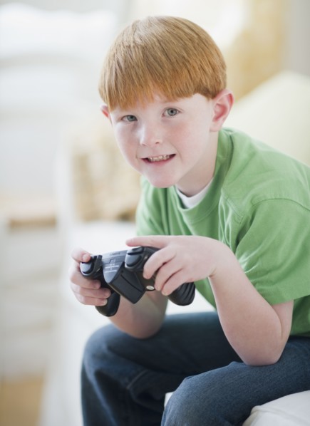 Portrait of boy (8-9) playing video game. Photo : Jamie Grill Photography