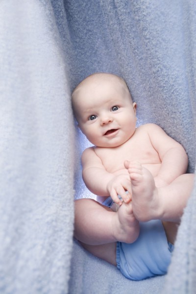 Portrait of baby boy (6-11 months) in bedclothes. Photo : Noah Clayton