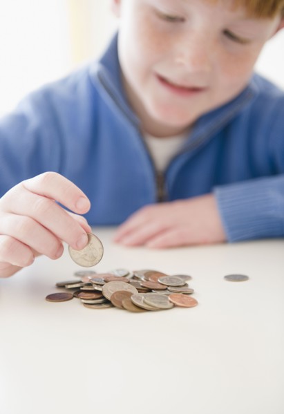 Portrait of boy (8-9) counting coins. Photo : Jamie Grill Photography