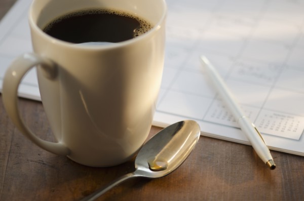 Cup of coffee beside calendar.