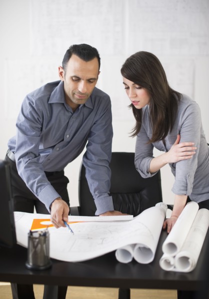 Business man and woman studying blueprints.