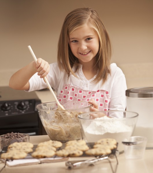 Portrait of girl (10-11) baking biscuits in kitchen. Photo : Mike Kemp