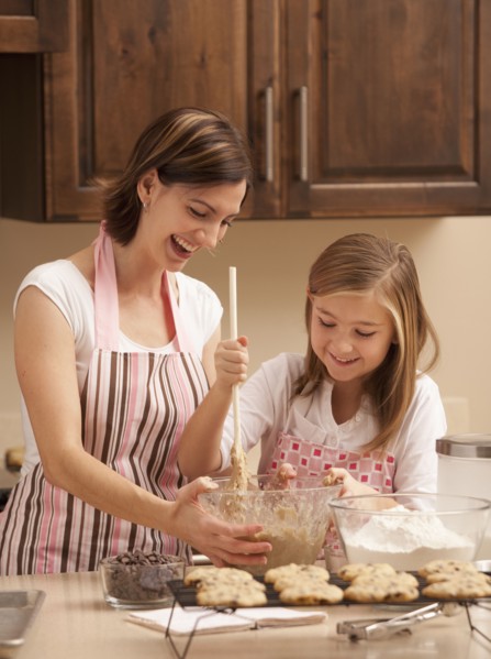 Mother baking with daughter (10-11) in kitchen. Photo : Mike Kemp