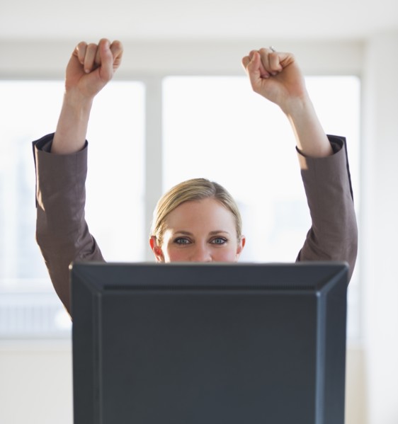 Businesswoman peeking from behind computer. Photo : Daniel Grill