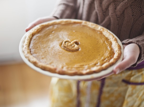 Close up of woman holding pumpkin pie.