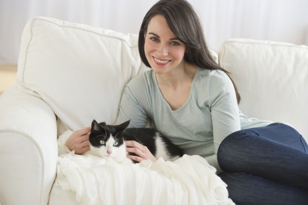 Portrait of woman with cat on sofa.