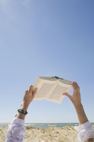 USA, Massachusetts, woman's hands on beach holding book. Photo : Chris Hackett