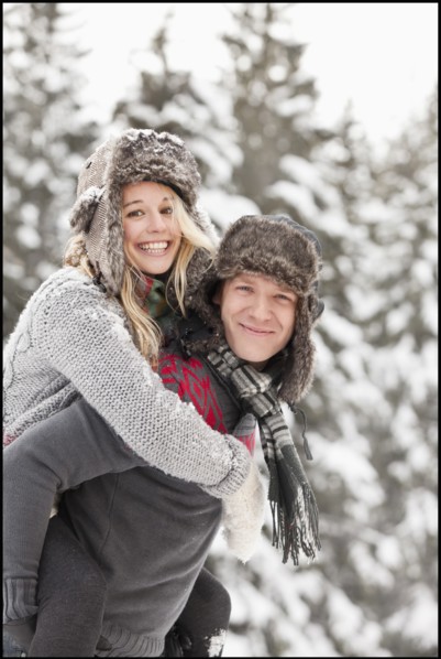 USA, Utah, Salt Lake City, man giving young woman piggy back ride in snow. Photo : Mike Kemp