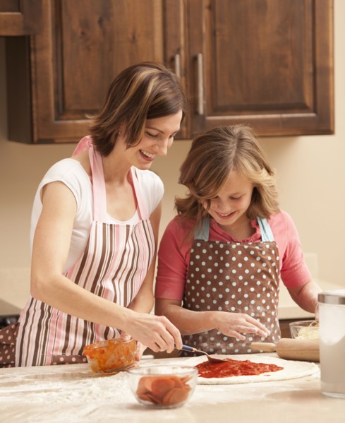 Mother and daughter (10-11) preparing pizza in kitchen. Photo : Mike Kemp