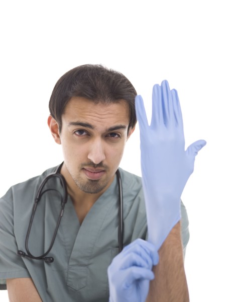 Young surgeon putting on protective gloves. Photo : Dan Bannister